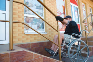 a disabled man on wheelchair trying to climb ramp entrance
