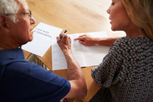 woman helping senior man to complete last will