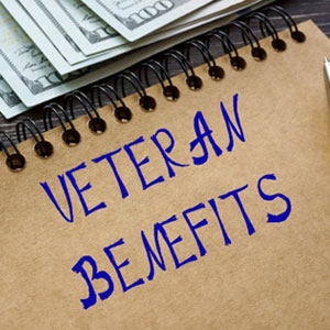Notepad with "veteran benefits" written on it, next to a stack of money